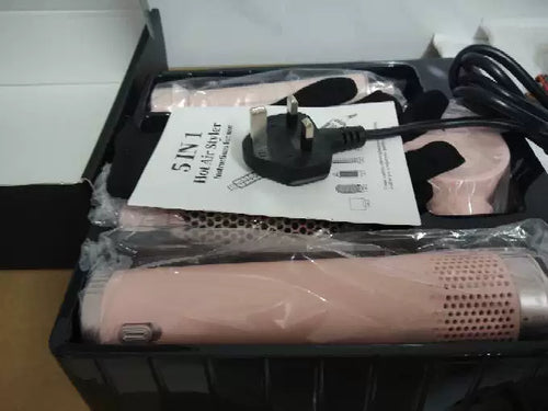 Pink 5-in-1 hot air styler packed in its box tray with UK 3-pin plug, heat-resistant glove and instruction leaflet