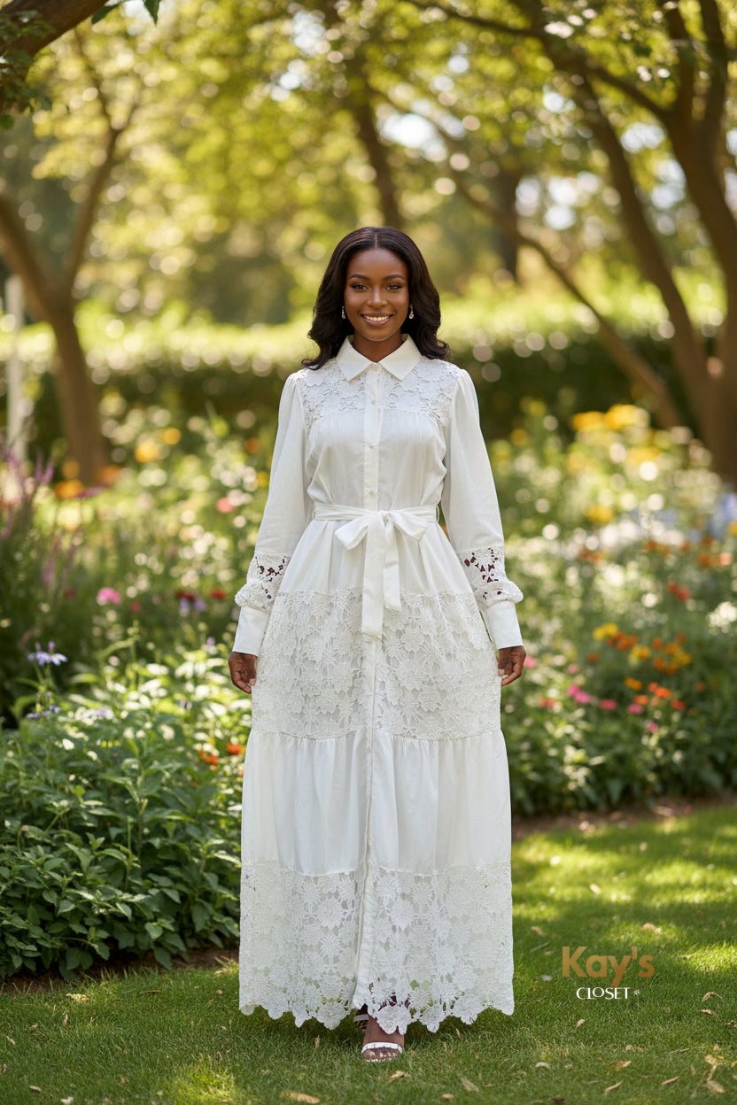 A woman models a brown tiered maxi dress with floral lace detailing and a matching waist tie, standing in front of a boutique counter with a 'SOIYSE' sign in the background.